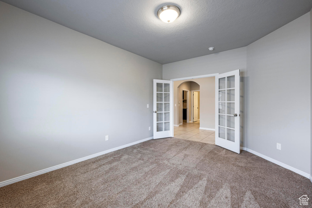 Carpeted empty room featuring french doors and a textured ceiling