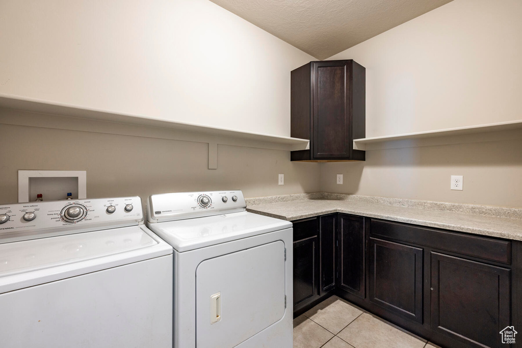 Laundry area with cabinets, washer hookup, light tile floors, and washer and dryer