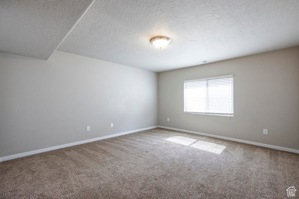 Spare room featuring carpet flooring and a textured ceiling