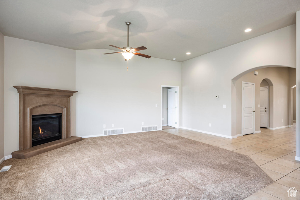 Unfurnished living room with high vaulted ceiling, ceiling fan, and light tile floors