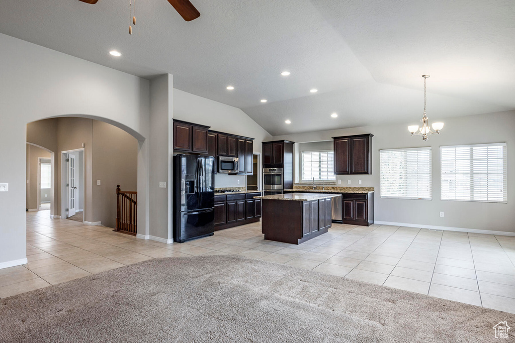 Kitchen with decorative light fixtures, appliances with stainless steel finishes, a kitchen island, light tile flooring, and ceiling fan with notable chandelier