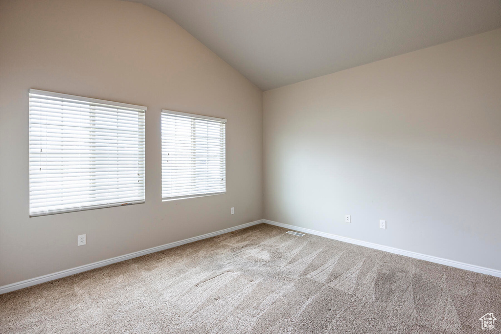 Unfurnished room with light carpet and vaulted ceiling