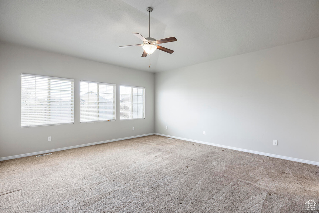 Spare room featuring plenty of natural light, ceiling fan, carpet, and lofted ceiling