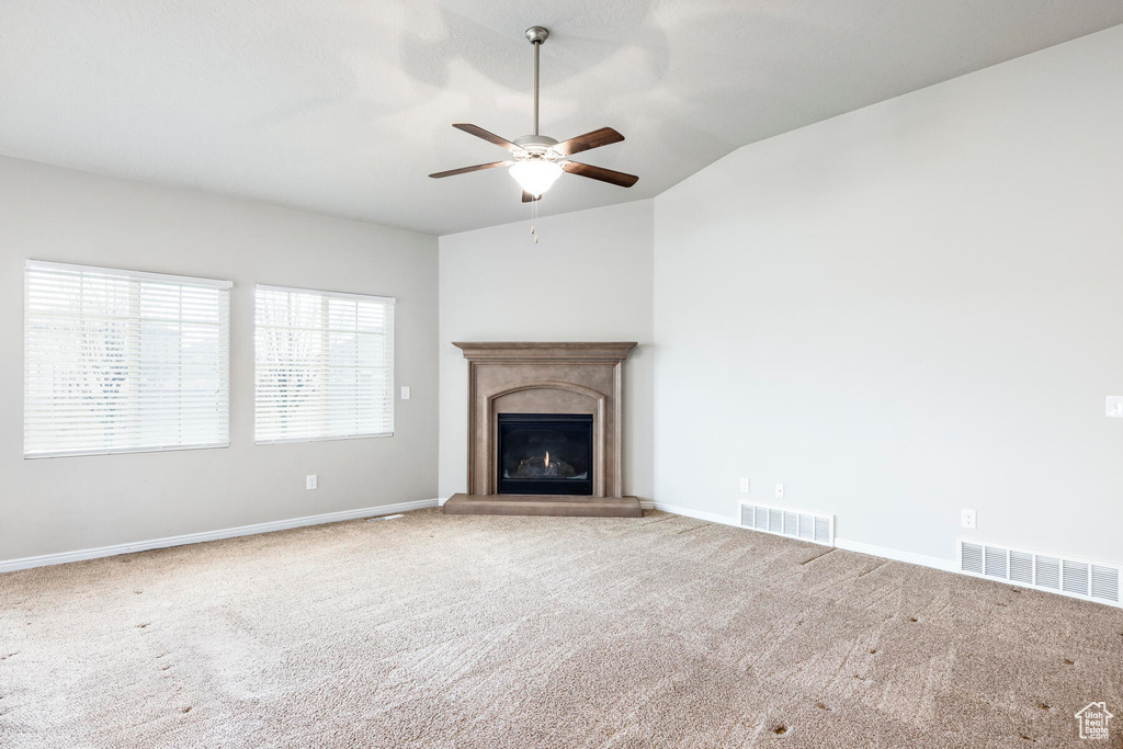 Unfurnished living room featuring lofted ceiling, ceiling fan, and carpet