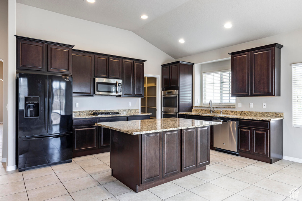 Kitchen with a center island, appliances with stainless steel finishes, dark brown cabinets, and lofted ceiling