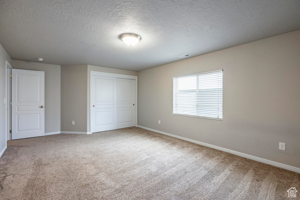 Unfurnished bedroom featuring a closet, carpet, and a textured ceiling
