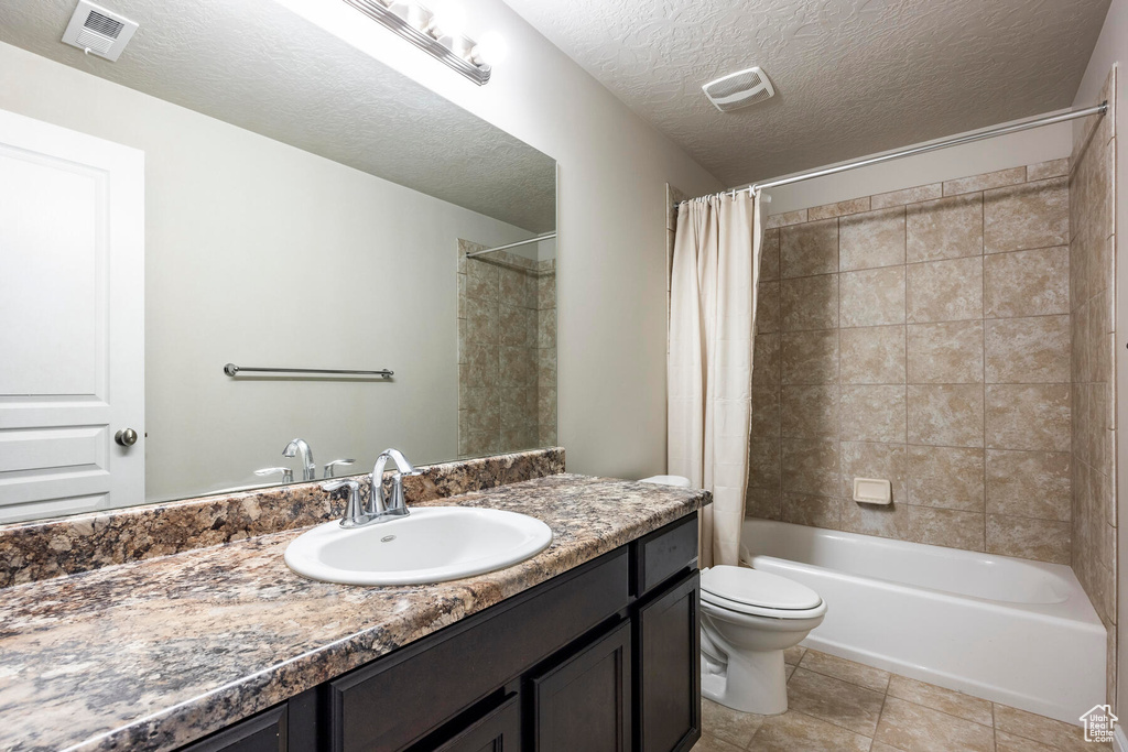 Full bathroom featuring a textured ceiling, toilet, tile floors, vanity, and shower / bathtub combination with curtain