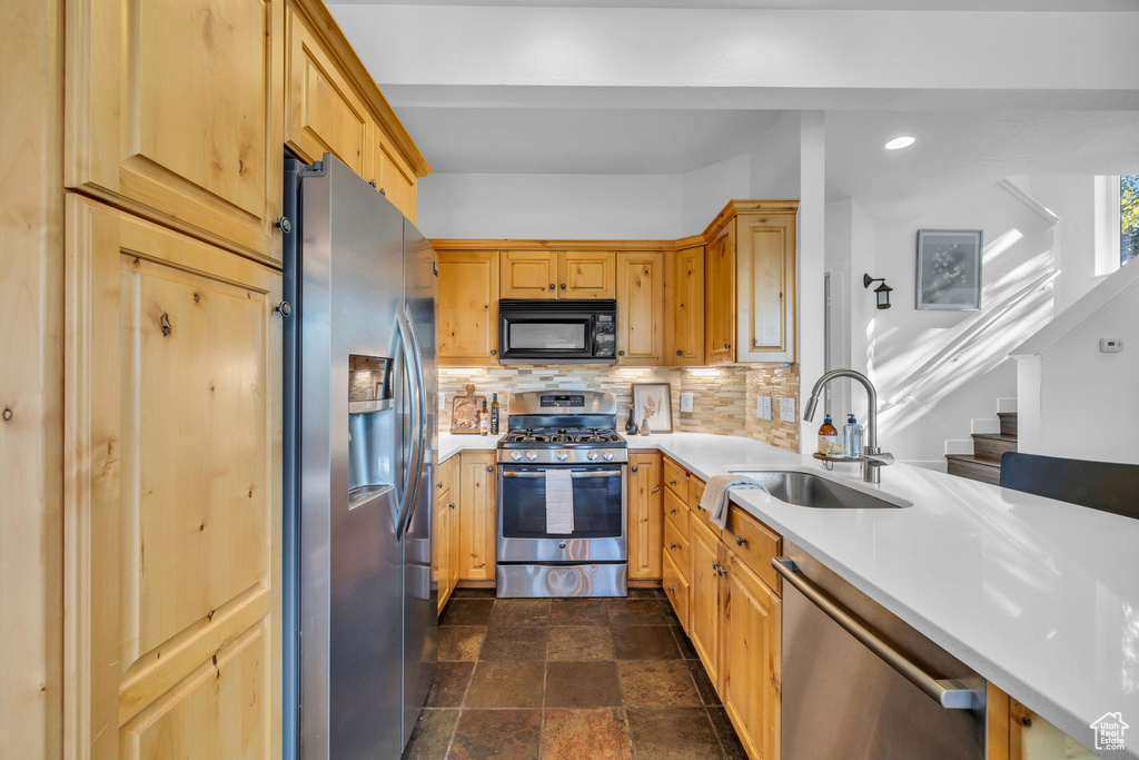 Kitchen with tasteful backsplash, stainless steel appliances, dark tile floors, and sink