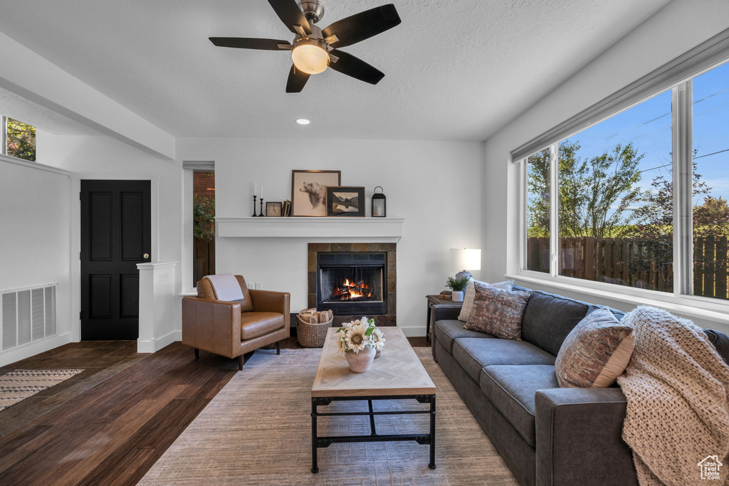Living room with a tile fireplace, dark hardwood / wood-style floors, and ceiling fan