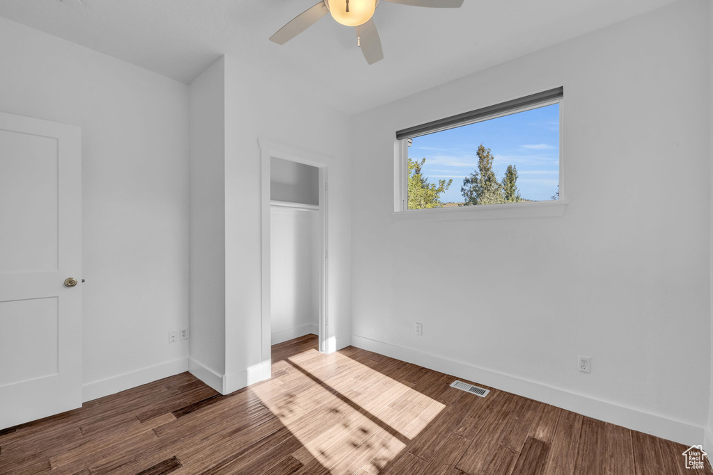 Unfurnished bedroom featuring dark hardwood / wood-style floors and ceiling fan
