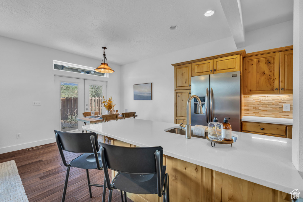 Kitchen featuring backsplash, stainless steel fridge, french doors, dark hardwood / wood-style flooring, and pendant lighting