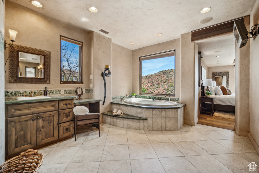 Bathroom featuring tiled tub, oversized vanity, and tile floors