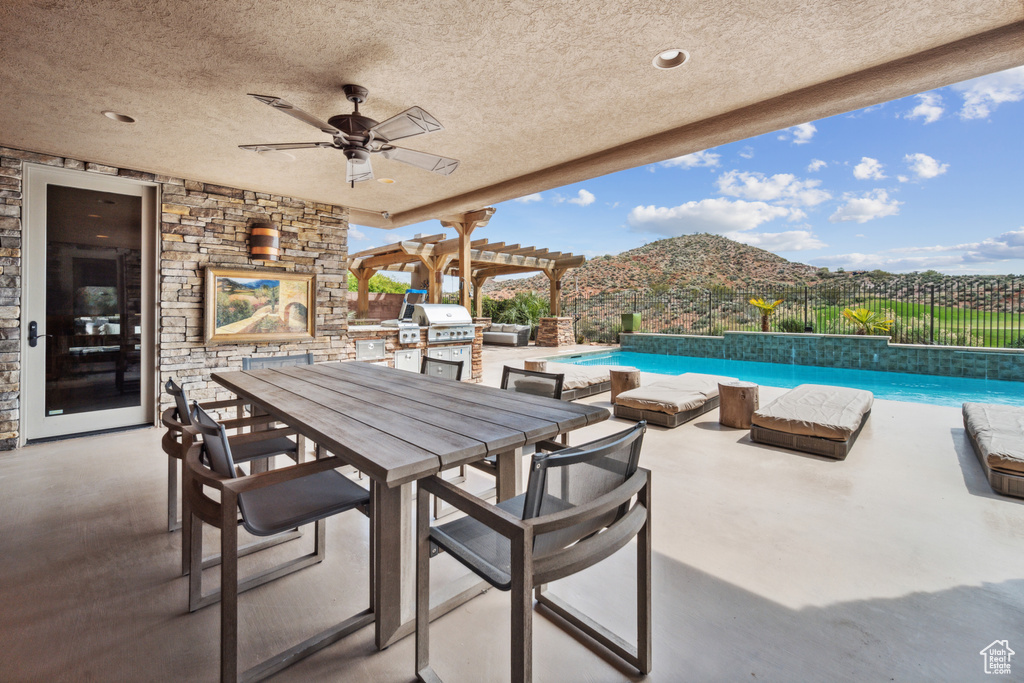 View of terrace featuring a mountain view, ceiling fan, a fenced in pool, and a fireplace