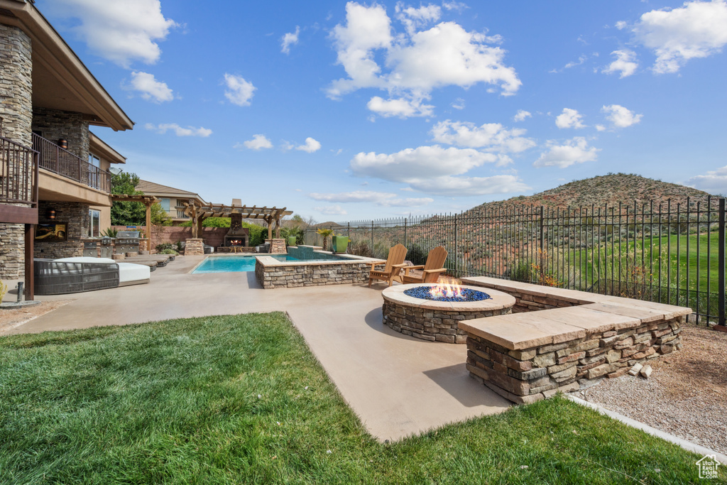 View of yard featuring a balcony, a mountain view, an outdoor fire pit, a fenced in pool, and a patio area