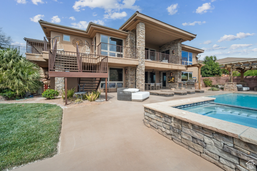 Rear view of property with a balcony, a swimming pool with hot tub, an outdoor living space, and a patio
