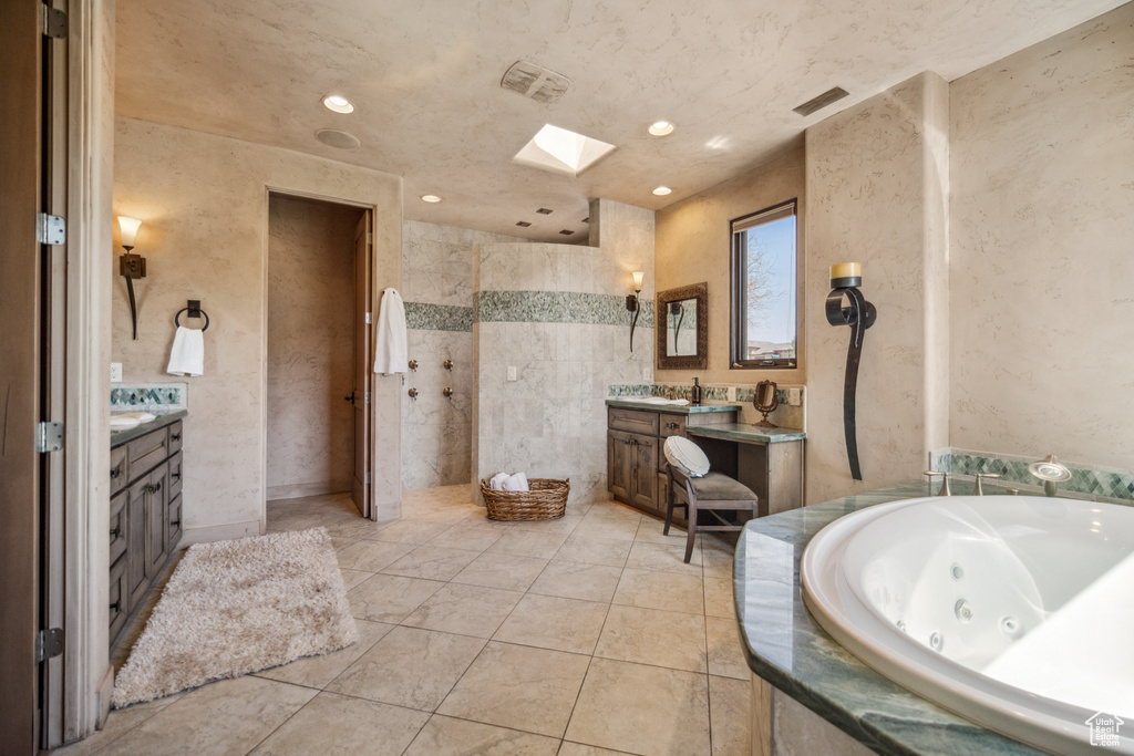 Bathroom featuring a skylight, tile floors, oversized vanity, and tile walls