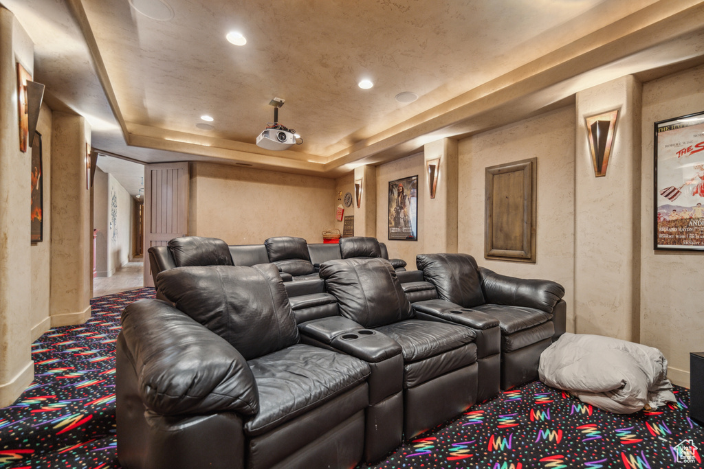 Carpeted cinema room with a raised ceiling