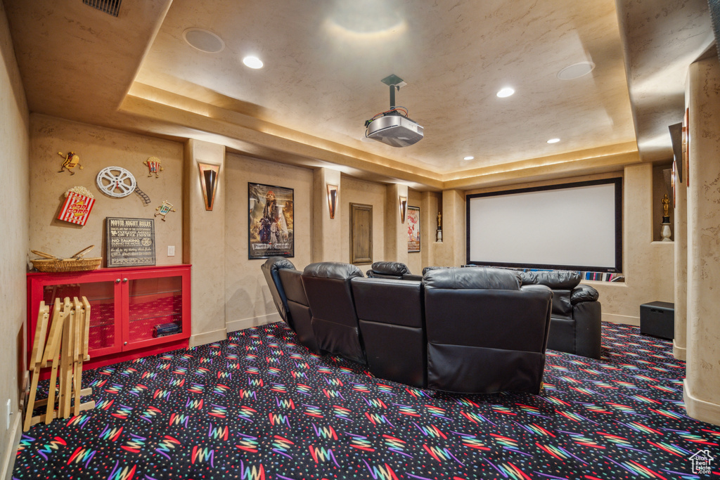 Cinema room with a raised ceiling and dark carpet