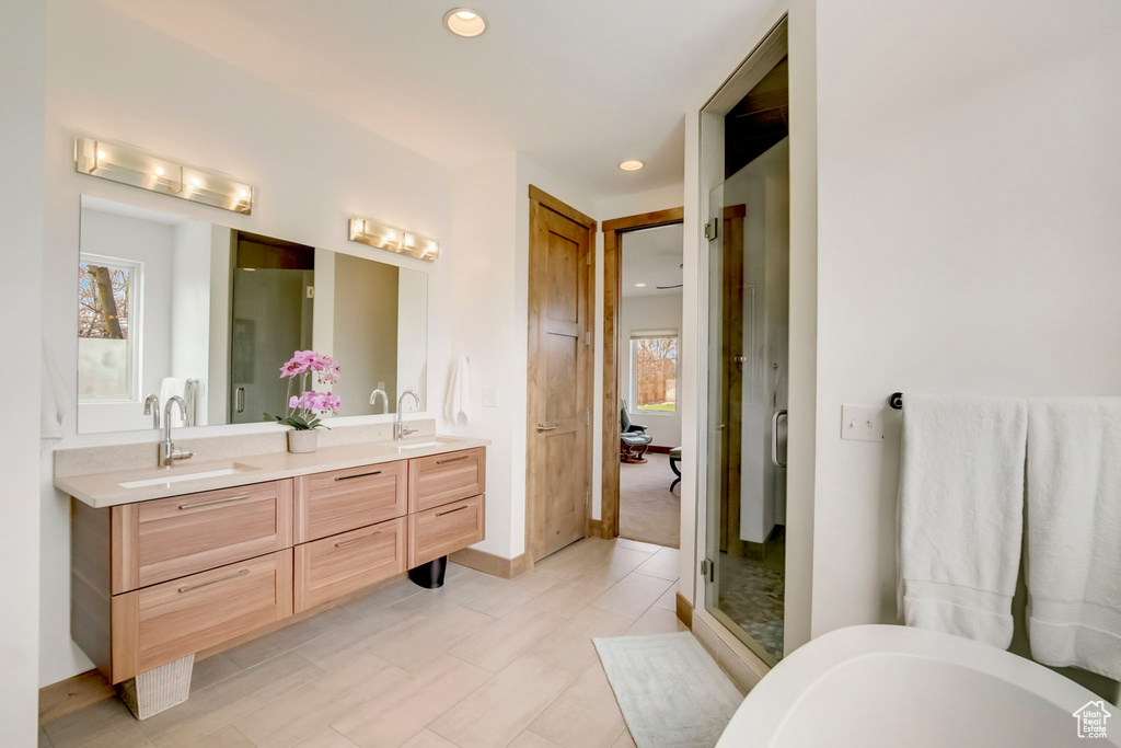 Bathroom with tile flooring, large vanity, double sink, and a wealth of natural light