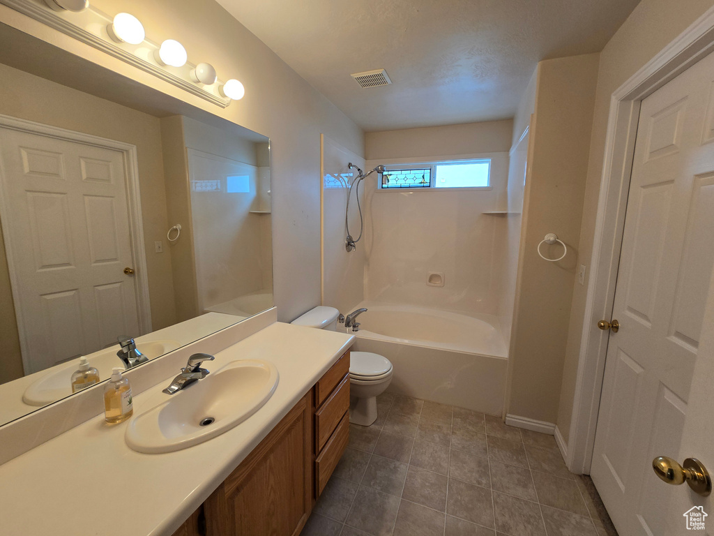 Full bathroom featuring toilet, vanity with extensive cabinet space, tile flooring, and tub / shower combination