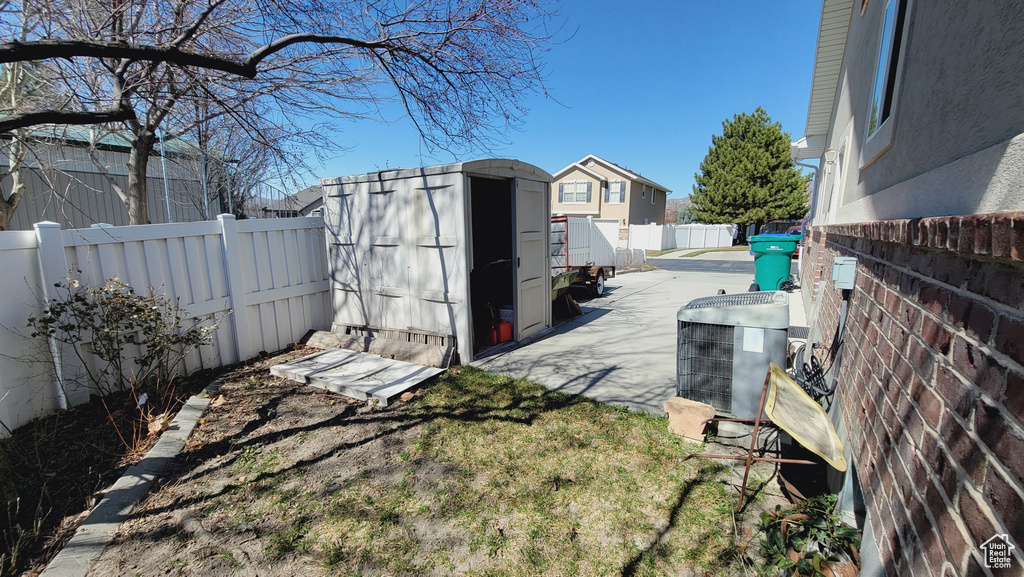 View of yard featuring a storage shed, central air condition unit, and a patio area