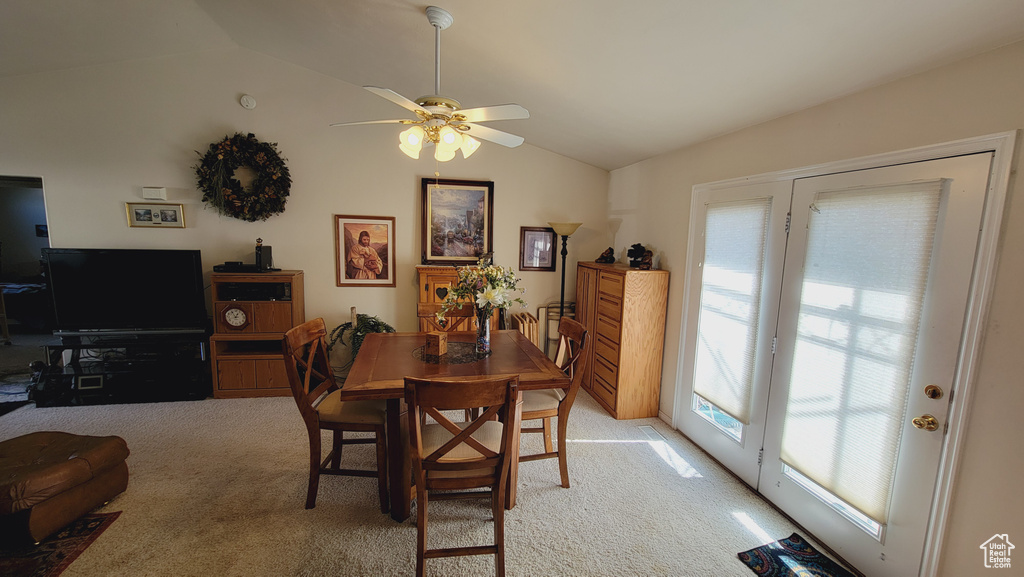 Carpeted dining area featuring vaulted ceiling and ceiling fan
