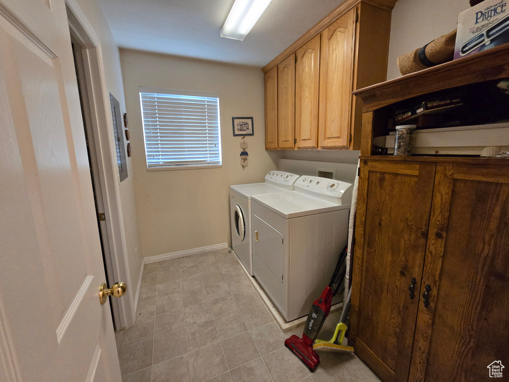 Clothes washing area featuring light tile flooring, separate washer and dryer, hookup for a washing machine, and cabinets