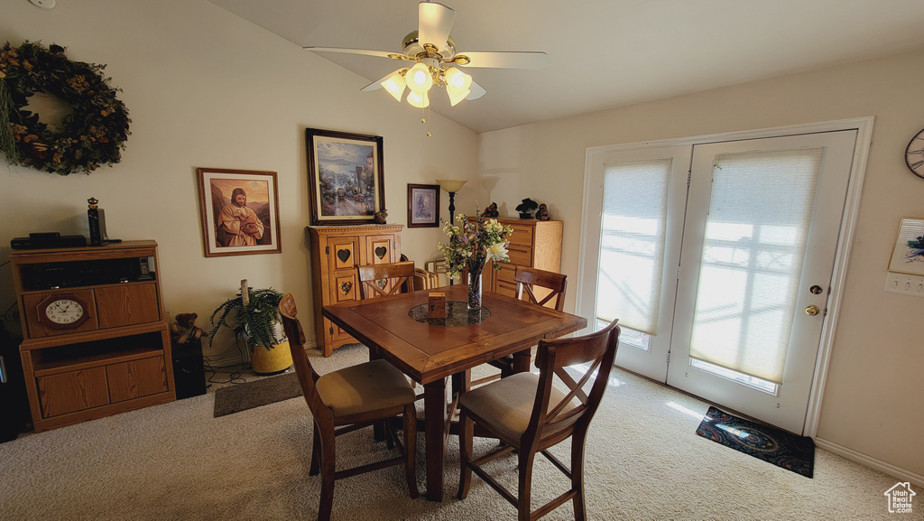 Carpeted dining space featuring vaulted ceiling and ceiling fan