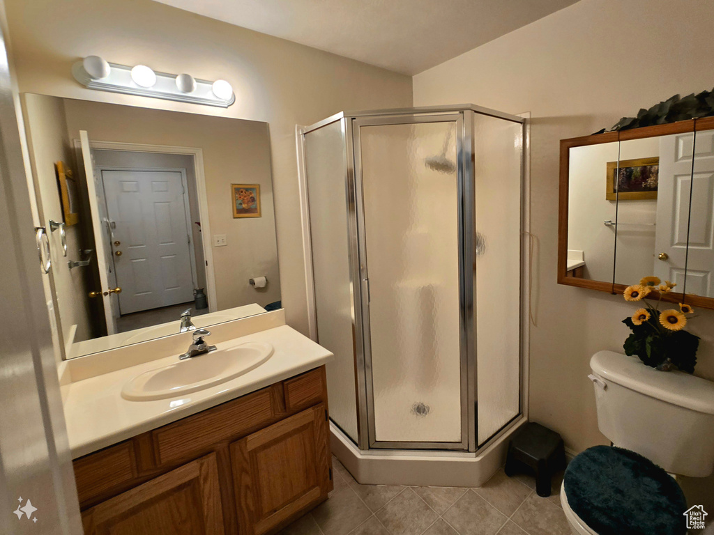 Bathroom with walk in shower, tile floors, vanity with extensive cabinet space, and toilet