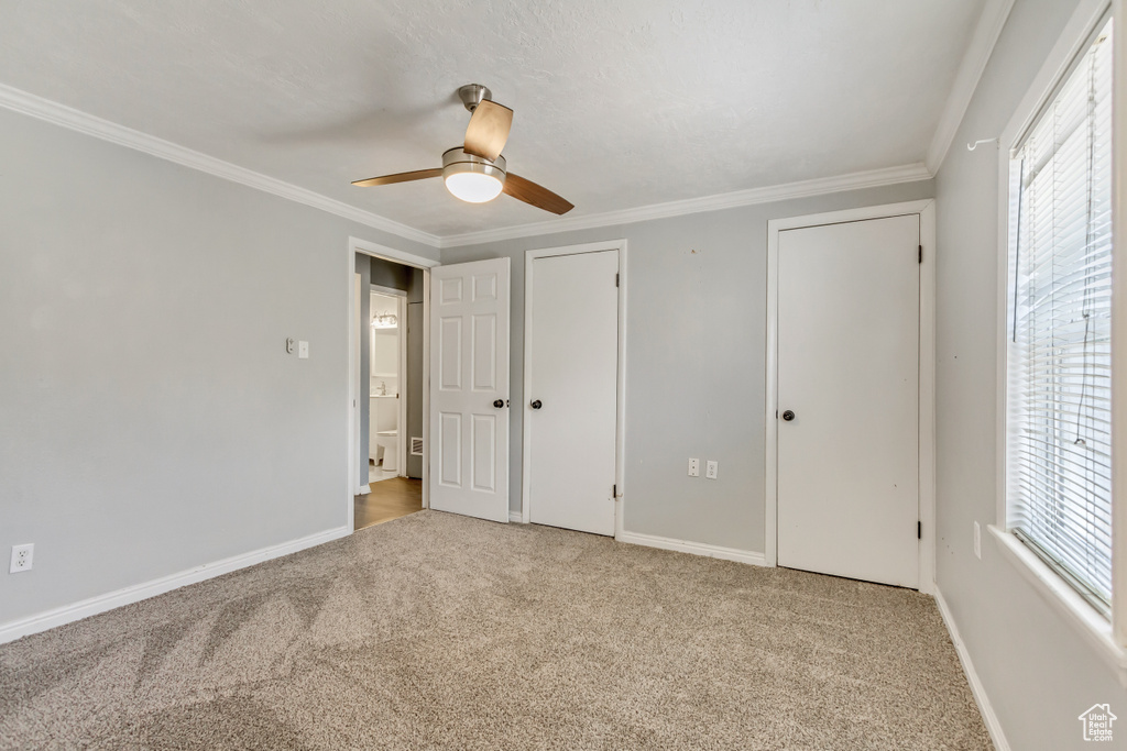 Unfurnished bedroom featuring light colored carpet, ornamental molding, and ceiling fan