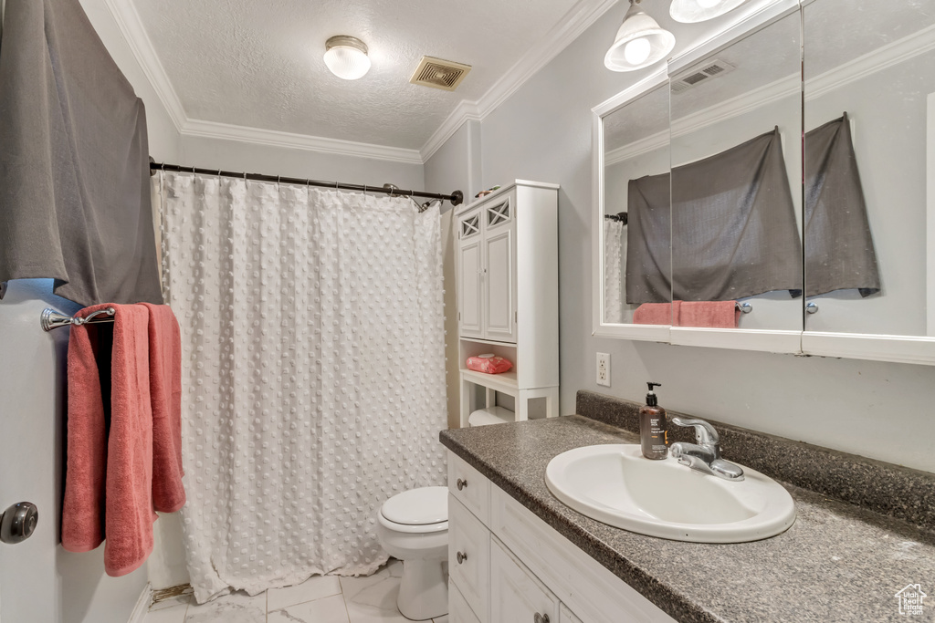 Bathroom featuring toilet, large vanity, a textured ceiling, ornamental molding, and tile floors
