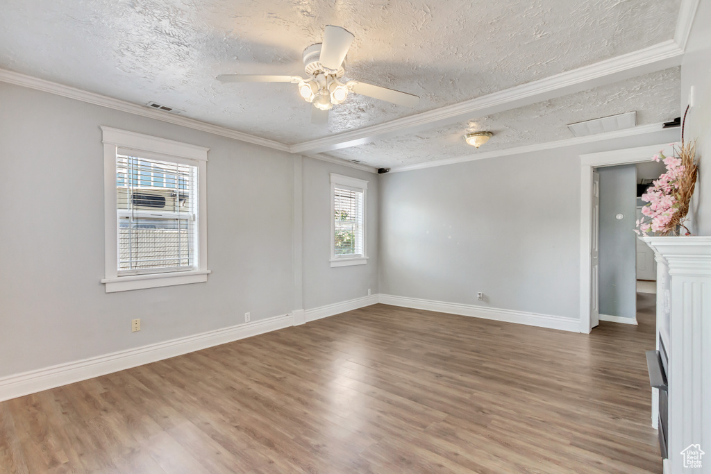 Unfurnished room featuring ceiling fan, hardwood / wood-style flooring, ornamental molding, and a textured ceiling