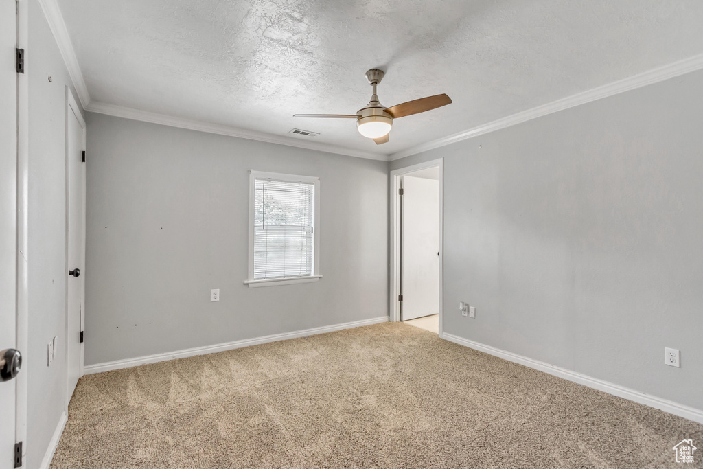 Carpeted spare room featuring crown molding and ceiling fan