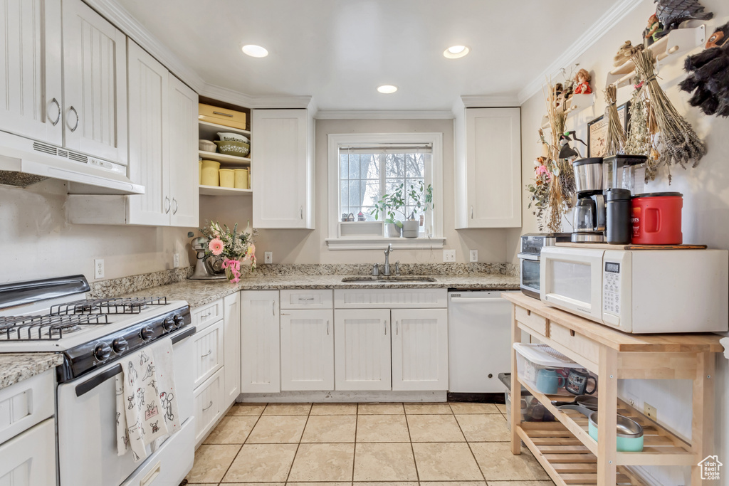 Kitchen with white appliances, sink, crown molding, light stone countertops, and white cabinetry