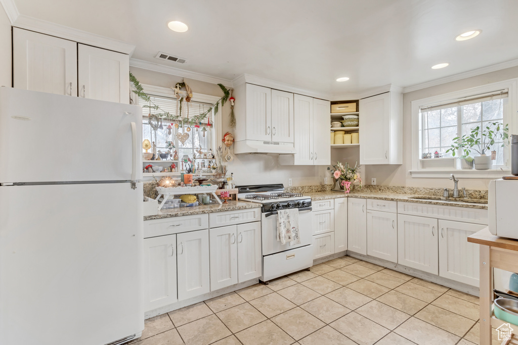 Kitchen featuring white cabinets, gas range oven, white fridge, and premium range hood