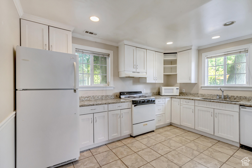 Kitchen with custom exhaust hood, white cabinets, white appliances, sink, and light tile patterned floors