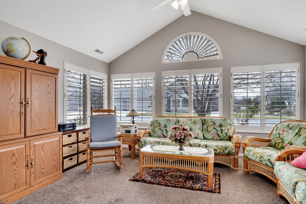Interior space featuring plenty of natural light, ceiling fan, high vaulted ceiling, and light colored carpet