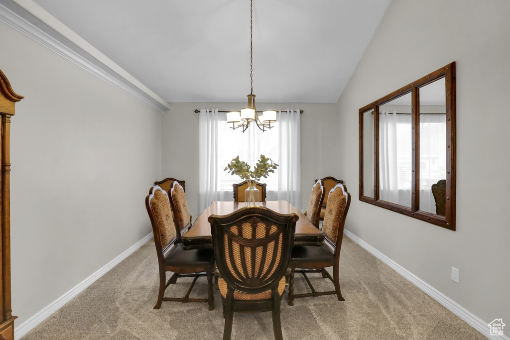 Carpeted dining space featuring an inviting chandelier and vaulted ceiling