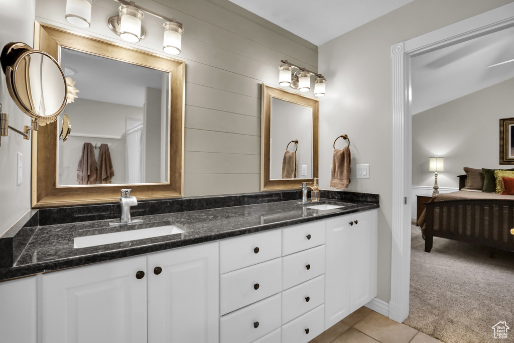 Bathroom featuring double sink, vanity with extensive cabinet space, and tile flooring