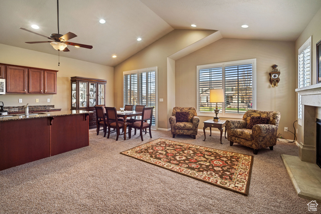 Living room with a high end fireplace, lofted ceiling, ceiling fan, and light colored carpet
