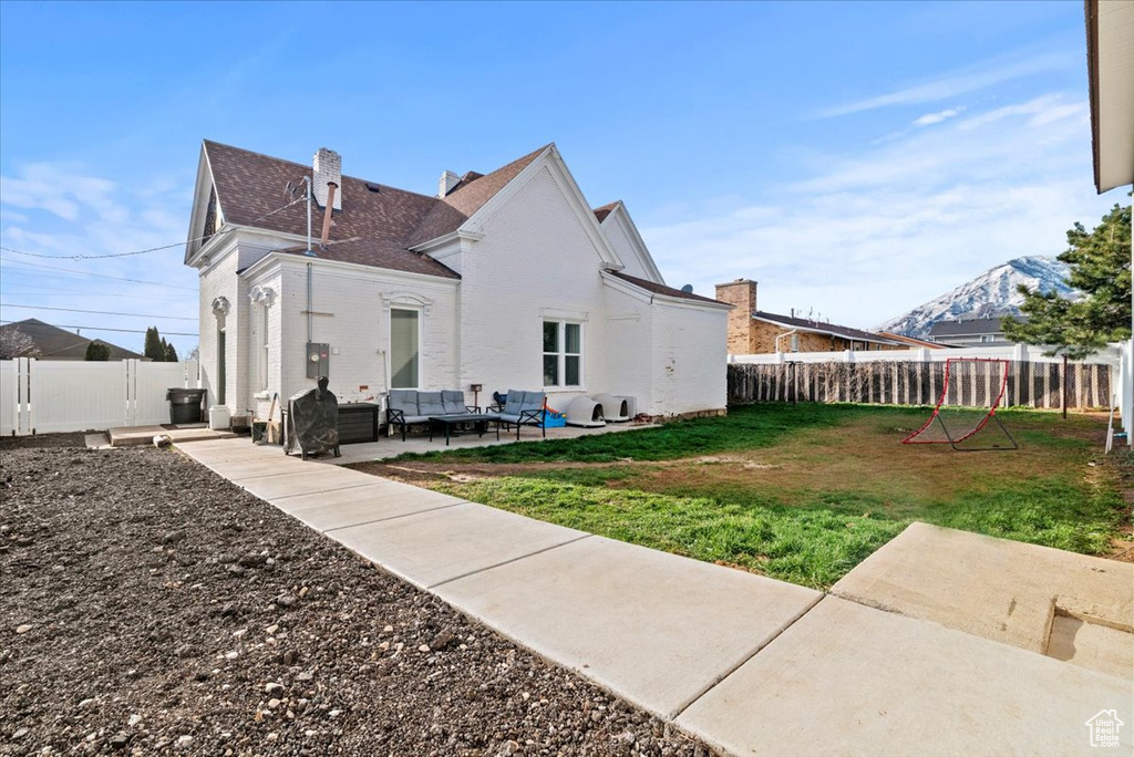Rear view of property with a lawn, a mountain view, outdoor lounge area, and a patio