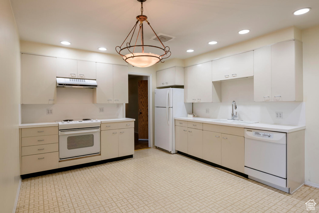 Kitchen featuring white appliances, light tile flooring, white cabinetry, backsplash, and hanging light fixtures