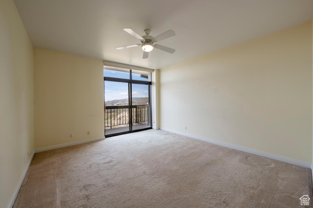 Carpeted spare room with ceiling fan and a wall of windows