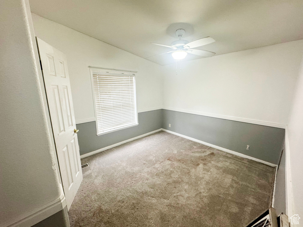 Carpeted spare room featuring vaulted ceiling and ceiling fan