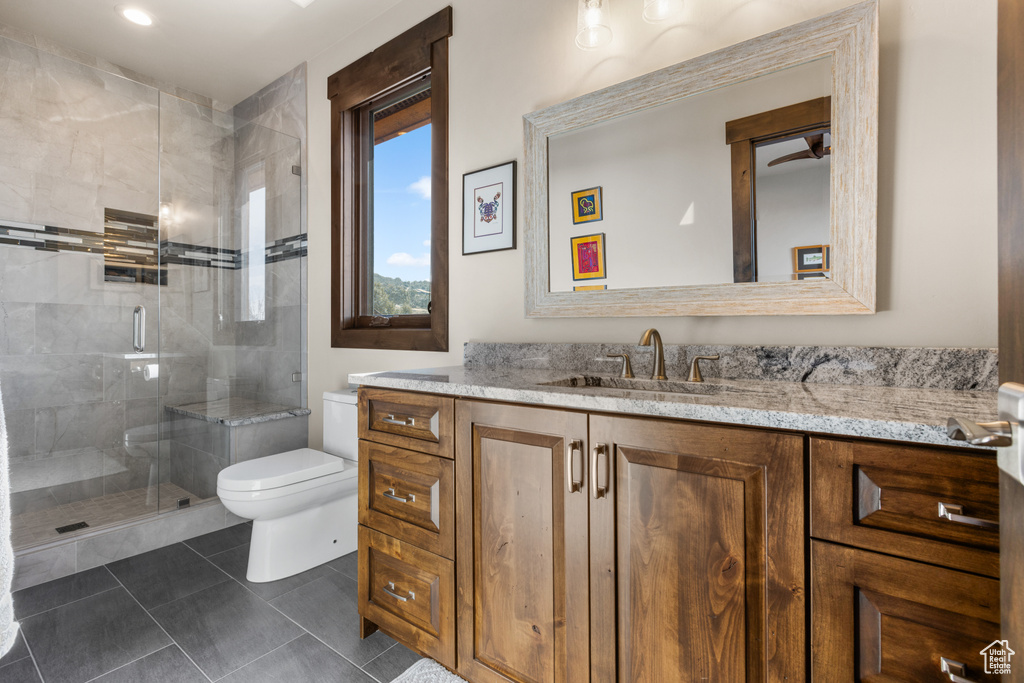 Bathroom featuring an enclosed shower, vanity, ceiling fan, tile flooring, and toilet