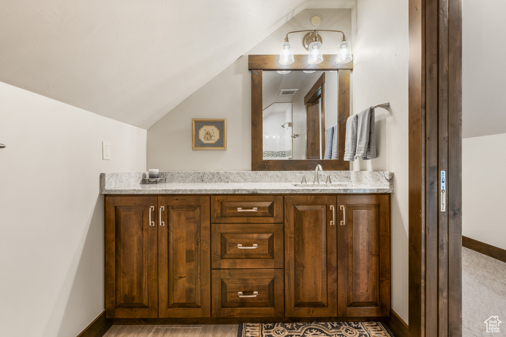 Bathroom featuring lofted ceiling, hardwood / wood-style floors, and double sink vanity