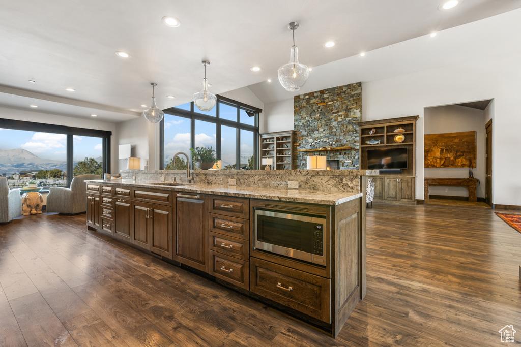 Kitchen with dark hardwood / wood-style floors, decorative light fixtures, stainless steel microwave, and sink