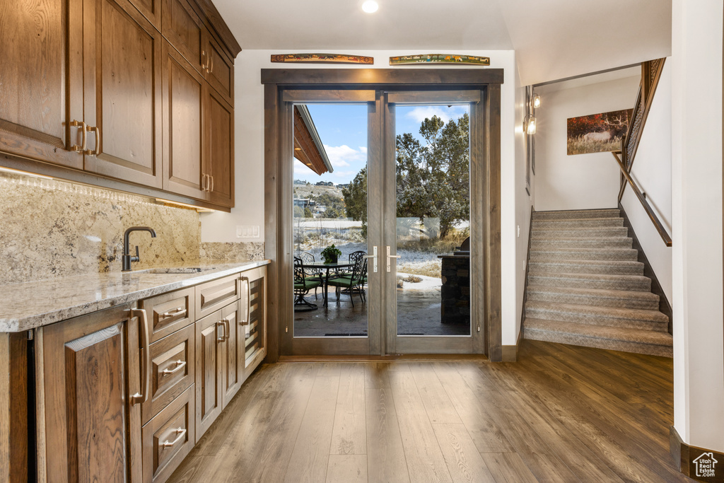 Kitchen featuring tasteful backsplash, dark hardwood / wood-style flooring, sink, and light stone counters