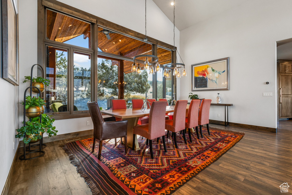 Dining room with a notable chandelier, plenty of natural light, high vaulted ceiling, and dark hardwood / wood-style floors