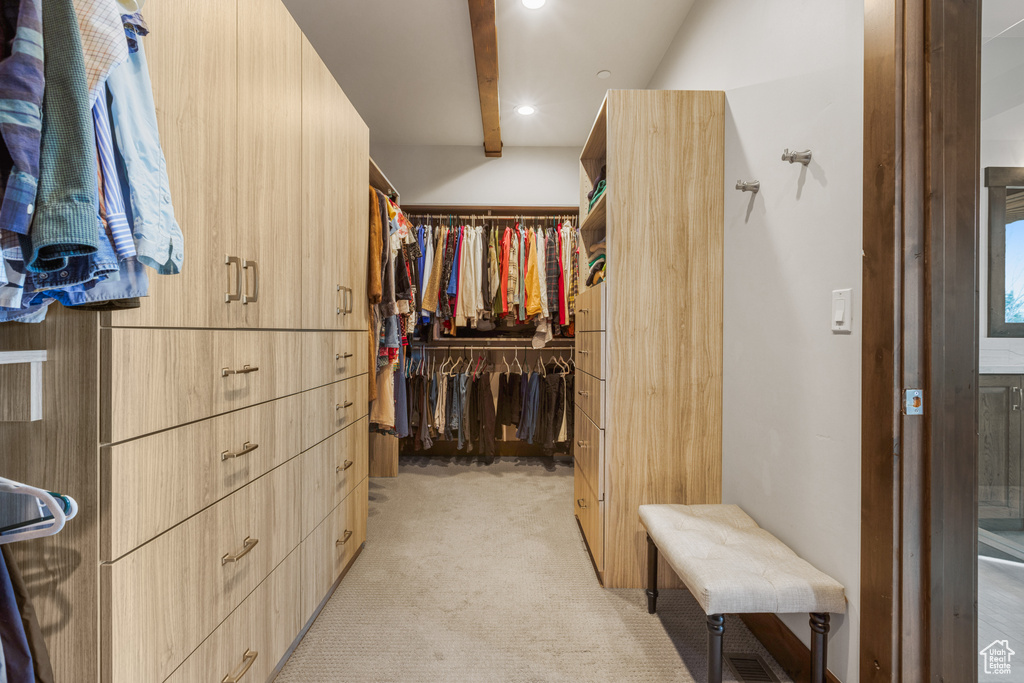 Walk in closet featuring light colored carpet and beam ceiling
